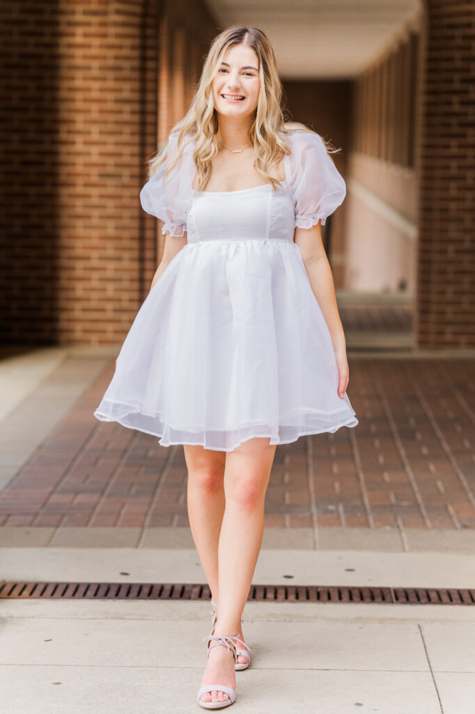 Texas State senior in front of the UAC red bricked area. 