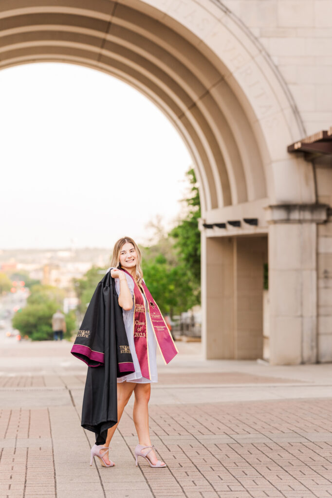 Texas State University Senior walking in front of the Arch. 