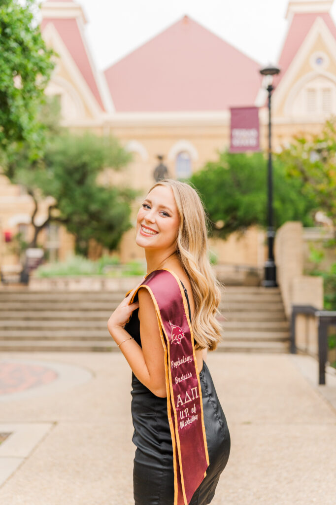 Texas State senior in front of Old Main building 