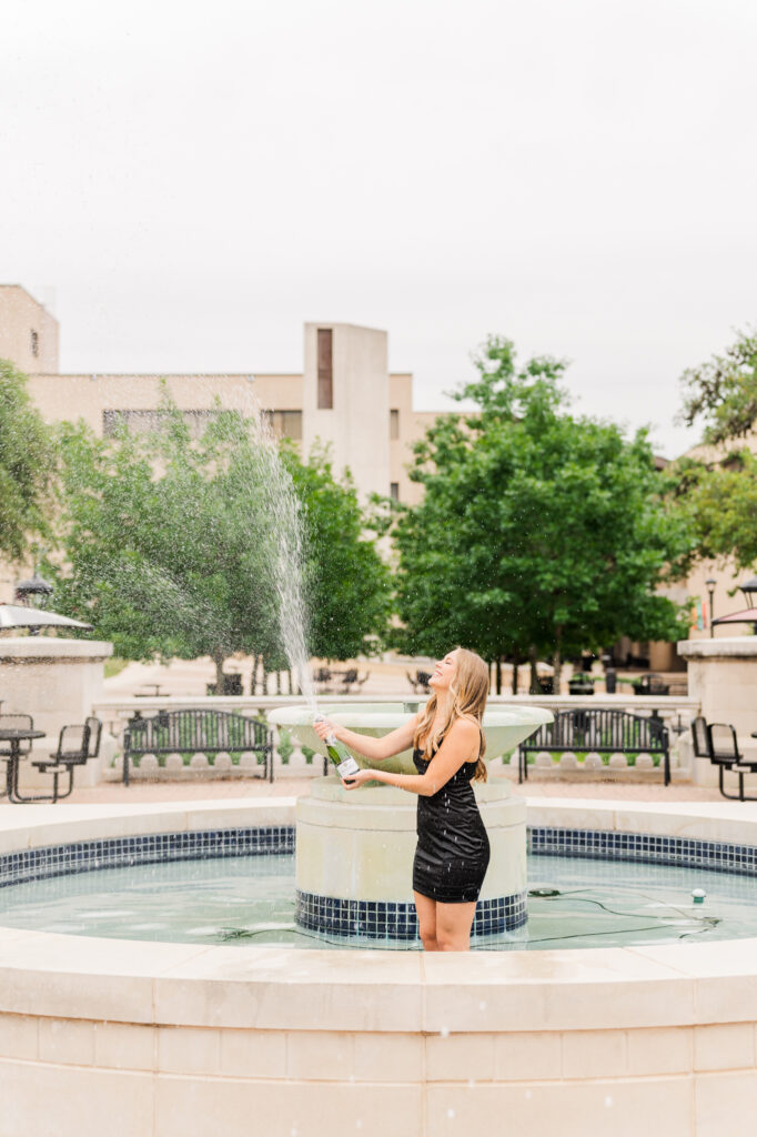 Texas State senior doing champagne pop in the fountain