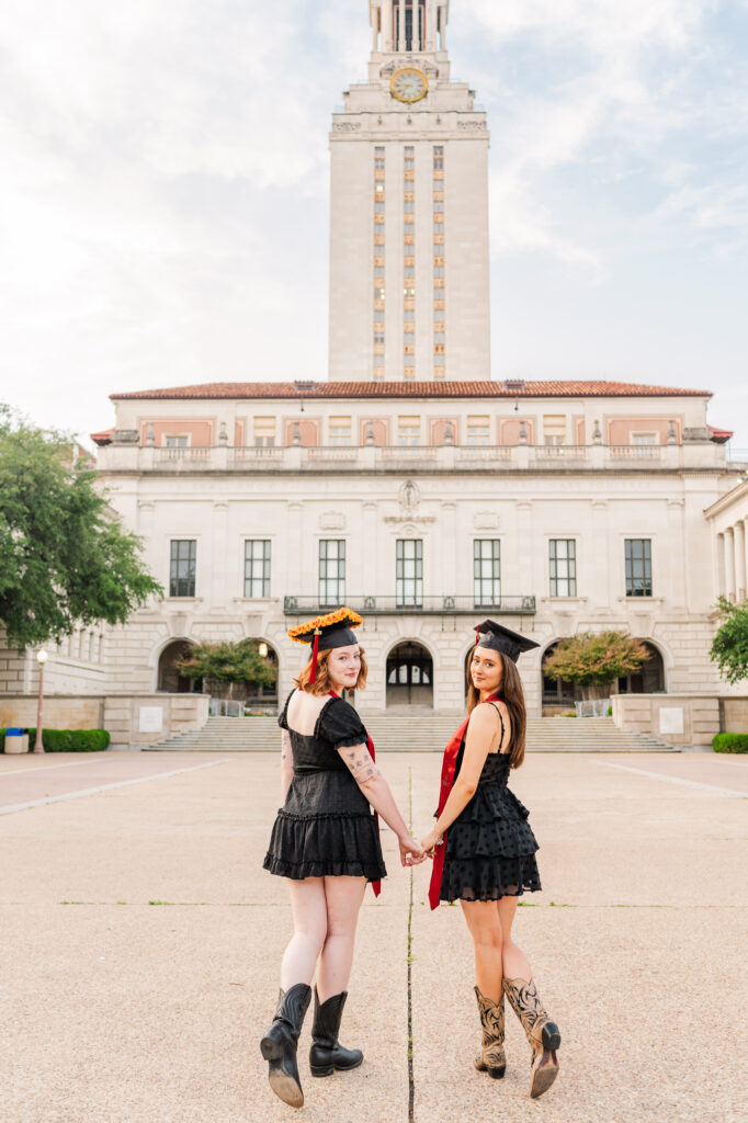 friends looking over shoulder in n front of tower during their UT Austin graduation session 