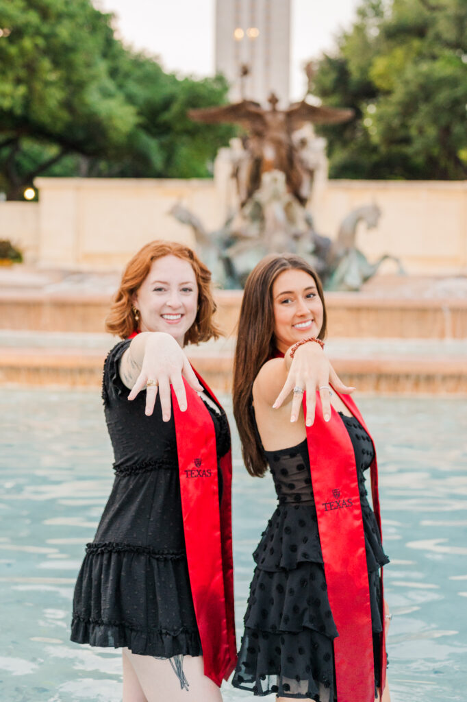 graduates holding out their graduation rings for their UT Austin graduation session
